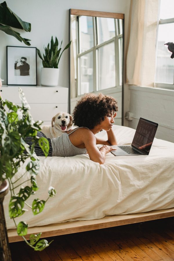 woman lying on bed typing on laptop virtual viewings